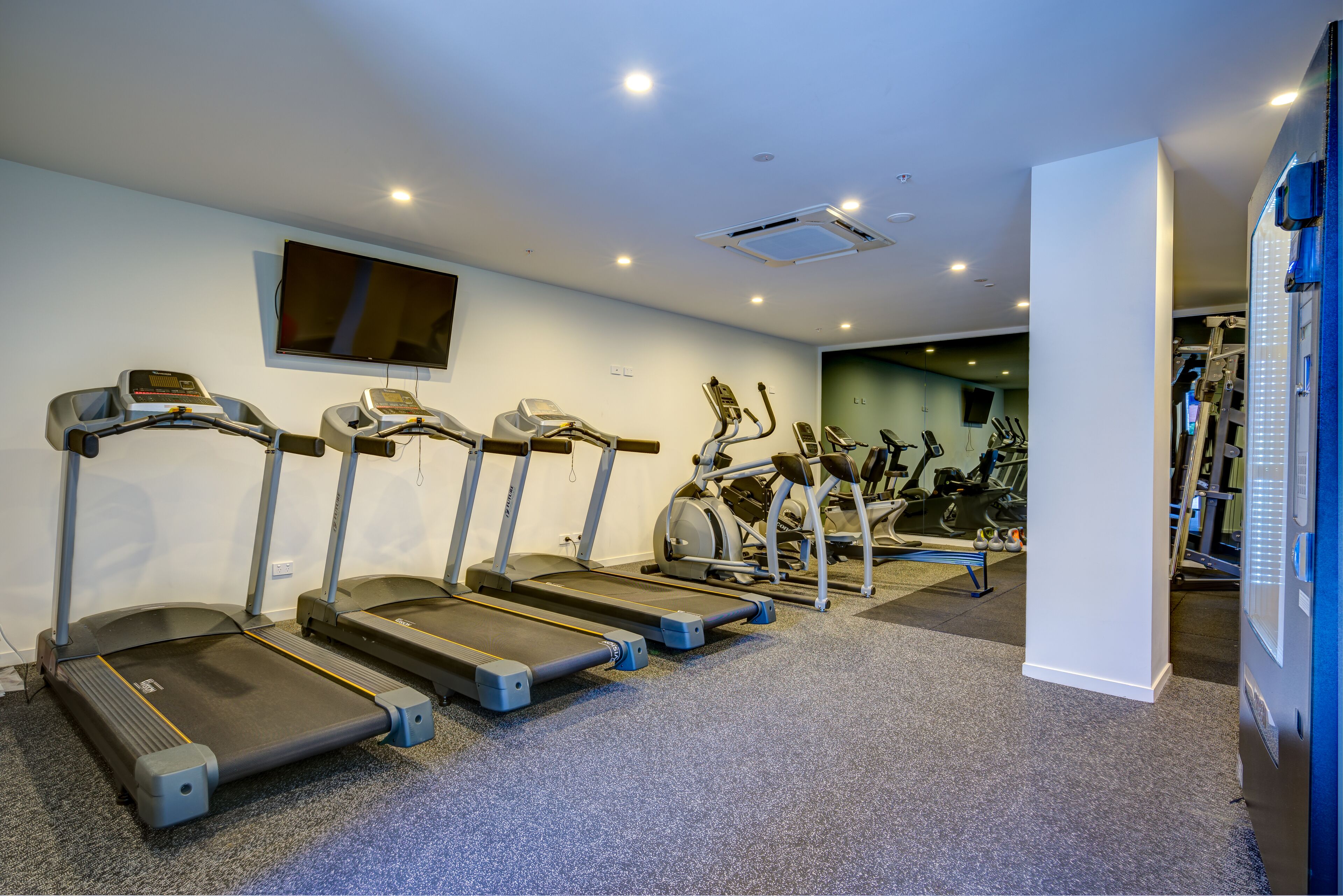 A gym with treadmills, stationary bikes, and exercise equipment.