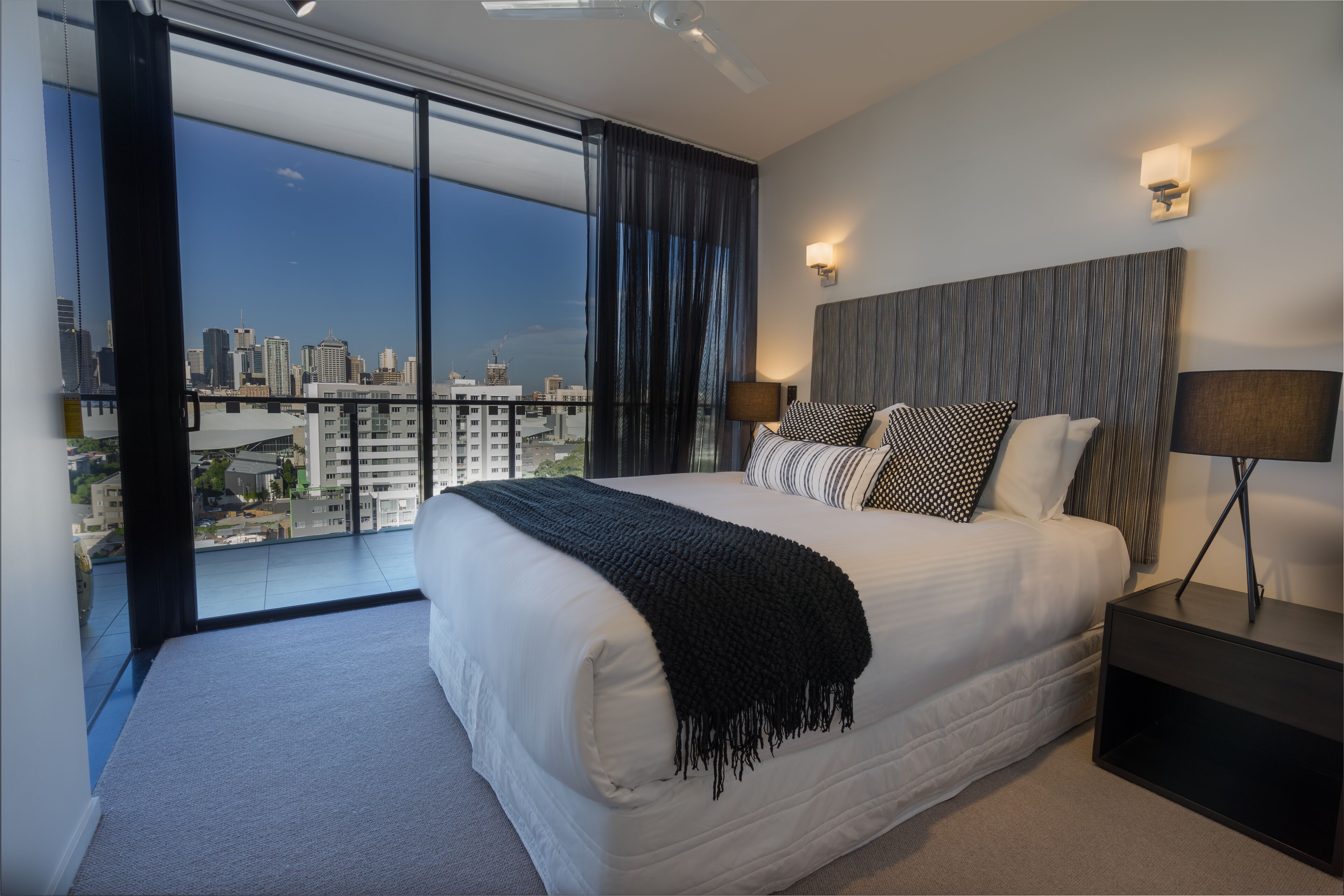 A modern hotel room with a large bed, a city view, and a balcony.