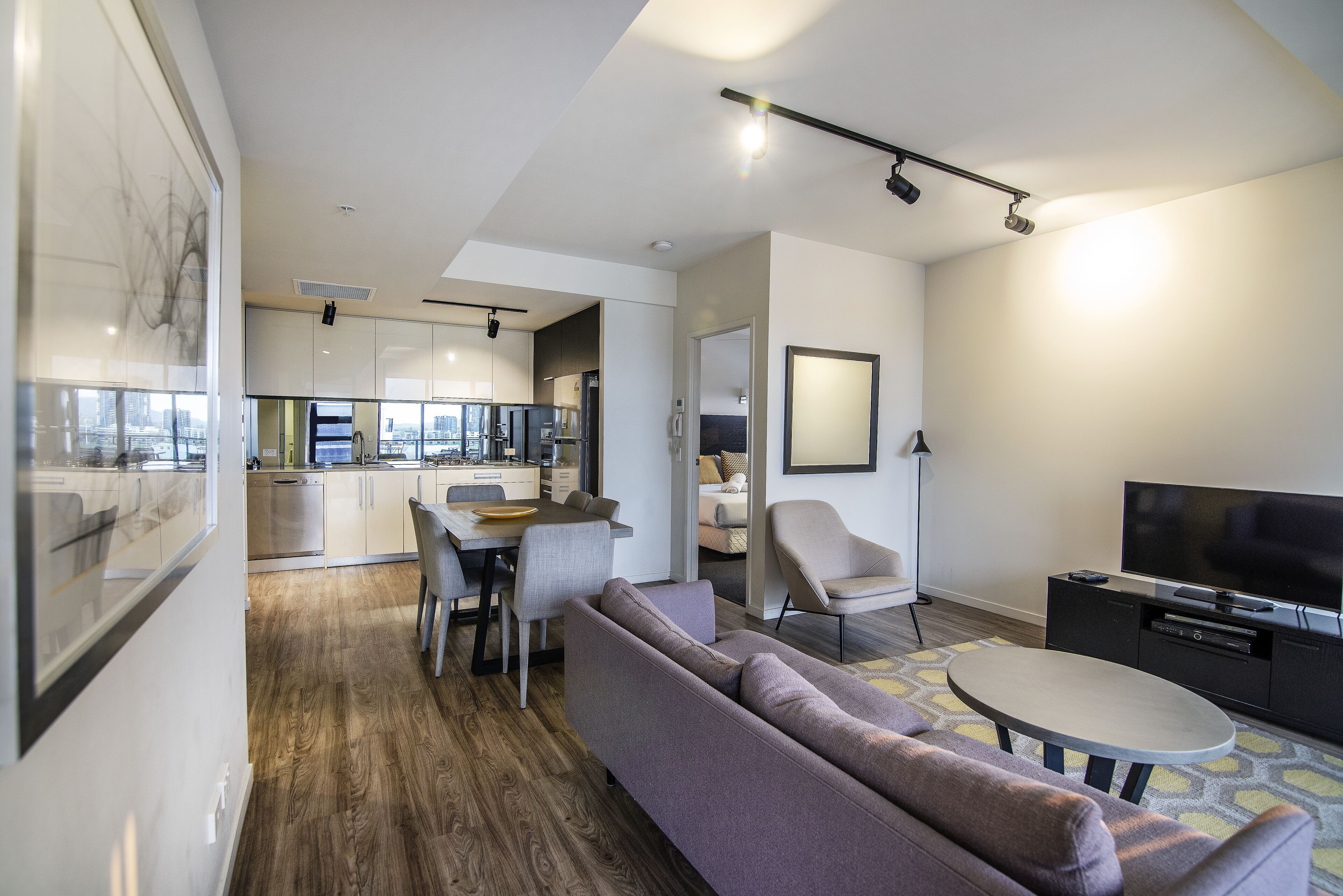 Un salon moderne avec un canapé, un coin repas et une cuisine en arrière-plan.