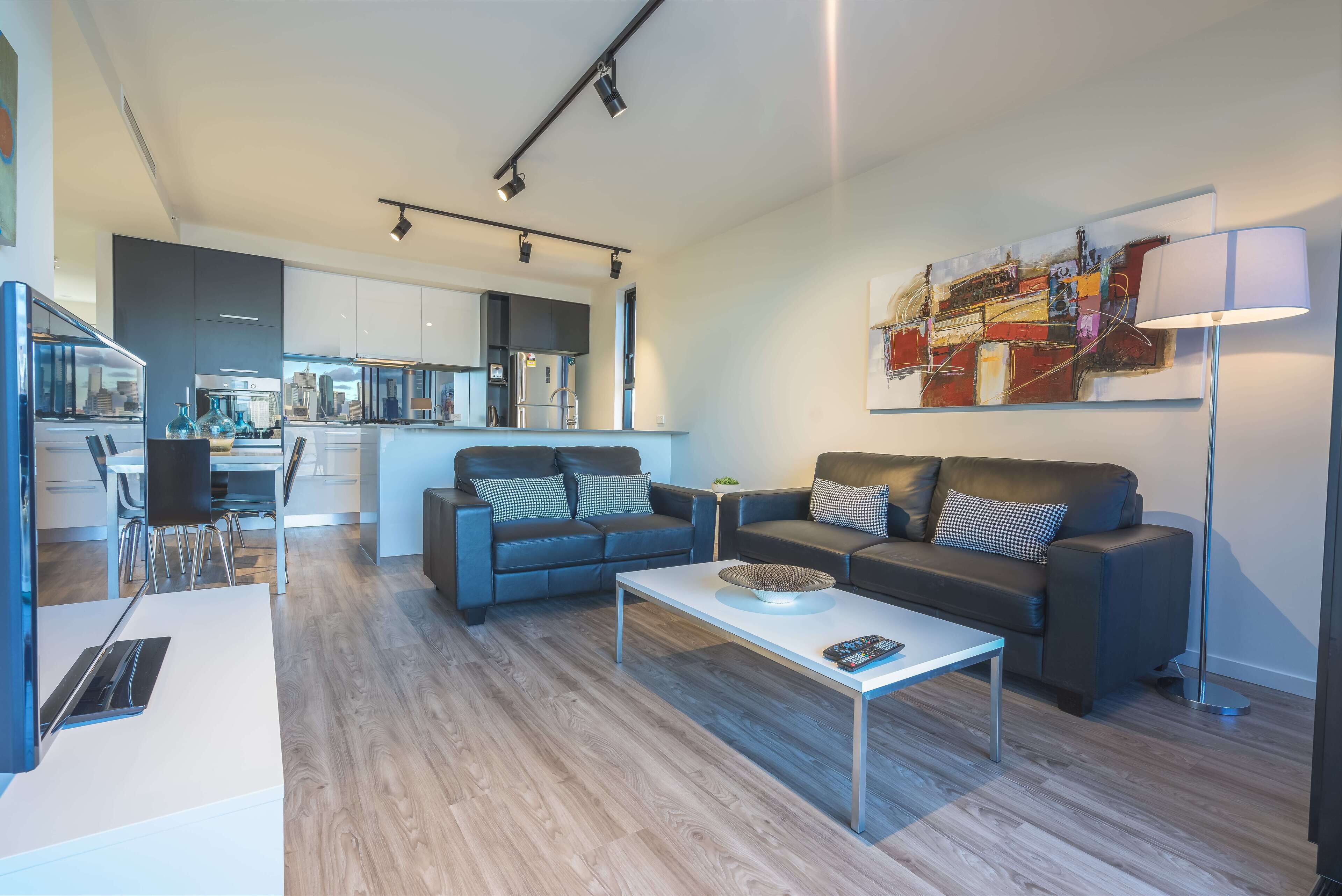 A modern living room with a sofa, coffee table, and a painting on the wall.