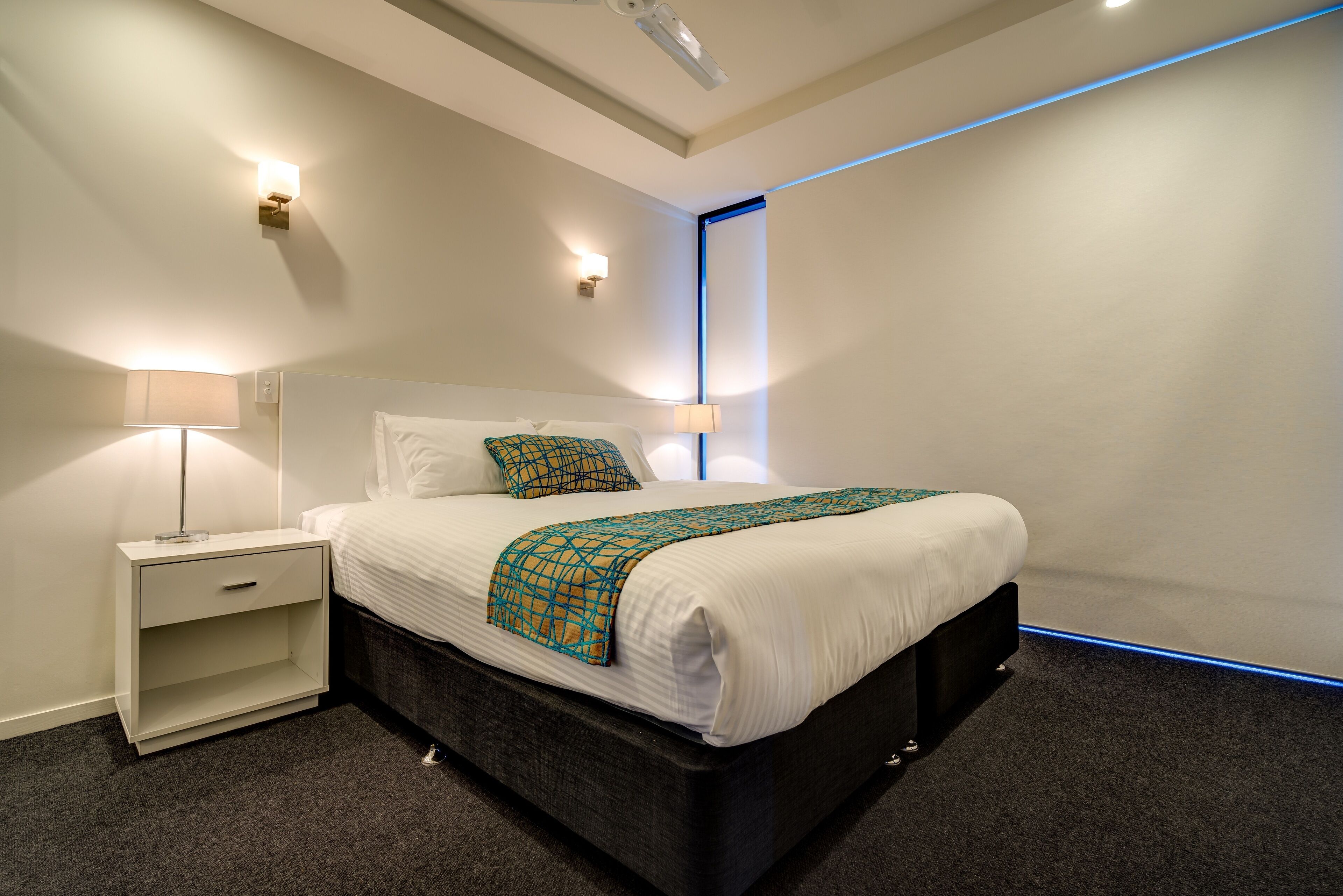 Ein modernes Hotelzimmer mit einem großen Bett, Nachttischen und einem Deckenprojektor.