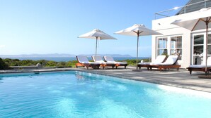 Una piscina al aire libre, sombrillas, tumbonas