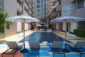 Relax by the central pool surrounded by lounge chairs and umbrellas, with a swan-shaped floatation device nearby.
