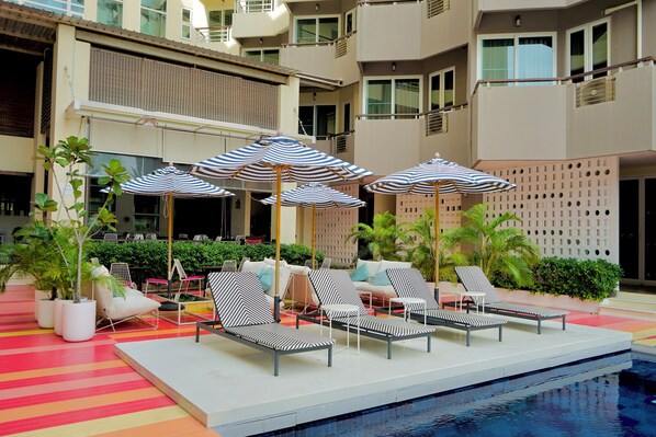 Relax by the pool surrounded by lounge chairs and lush greenery.