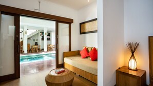 A modern living room with a sofa, a round wooden coffee table, and a floor lamp. - Sedasa Lodge (Tibubeneng)