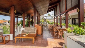 A covered outdoor seating area with wooden furniture and potted plants. - Sedasa Lodge (Tibubeneng)