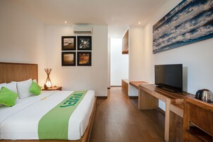 Habitación de hotel con una cama, un escritorio, un televisor y un cuadro grande en la pared.