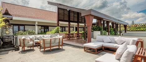 A modern outdoor patio with a mix of seating options, including a sofa, chairs, and a dining area.