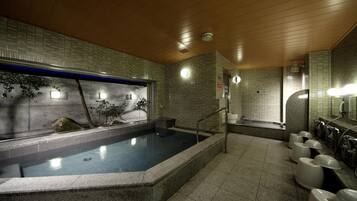 A modern spa with a large hot tub, tiled walls, and a wooden ceiling.