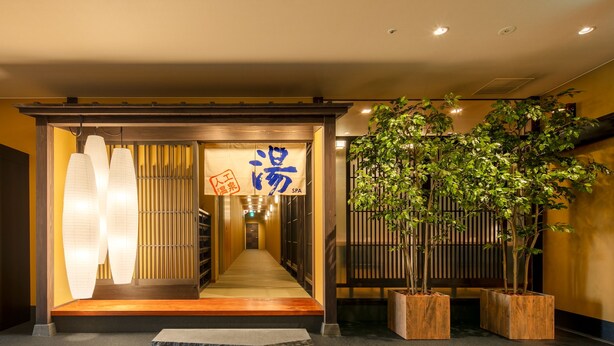 L’entrée d’un hôtel, avec une rampe en bois, un comptoir d’accueil et un grand arbre en pot.