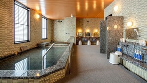 Un espace spa moderne doté d’un grand bain à remous, d’une zone de douche séparée et d’un comptoir d’accueil.