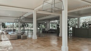 Un espacio interior amplio con techo alto, ventanas grandes y suelo de baldosas.