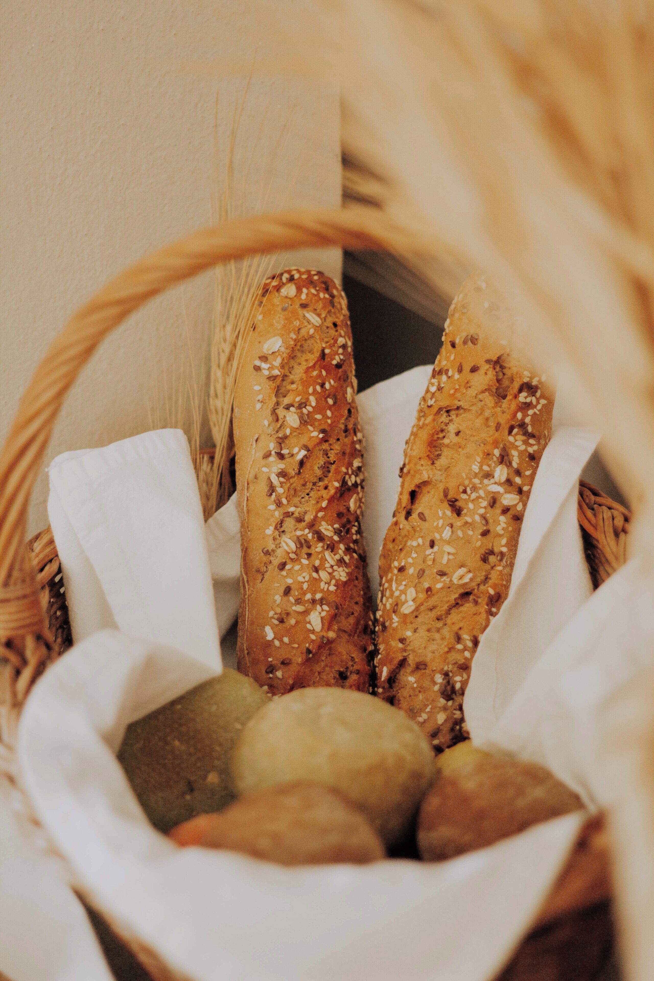 A basket containing several loaves of bread with sesame seeds, placed on a white cloth.