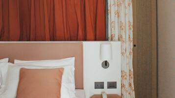 A hotel room with a bed, a nightstand, a telephone, and a wardrobe.
