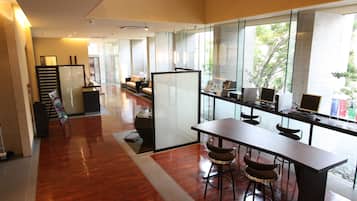 Un espacio de oficina moderno con una mesa larga, taburetes de bar y una partición de vidrio.