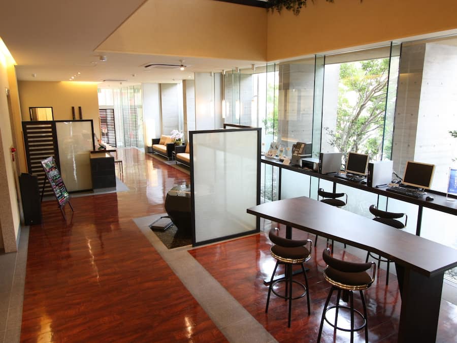 A modern office space with a long table, bar stools, and a glass partition.