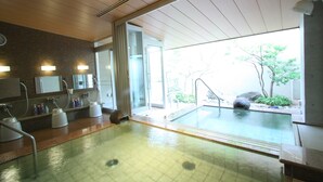 Uma área interna de piscina moderna com parede de vidro, teto de madeira e parede de pedra.