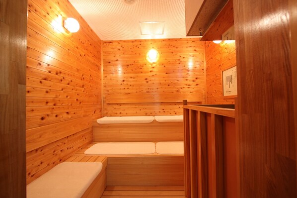 A wooden sauna with benches and a wooden wall. - Uozu Manten Hotel Ekimae (Uozu)