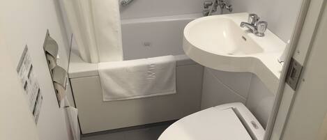 Een kleine badkamer met een wit toilet, een badkuip en een wastafel.