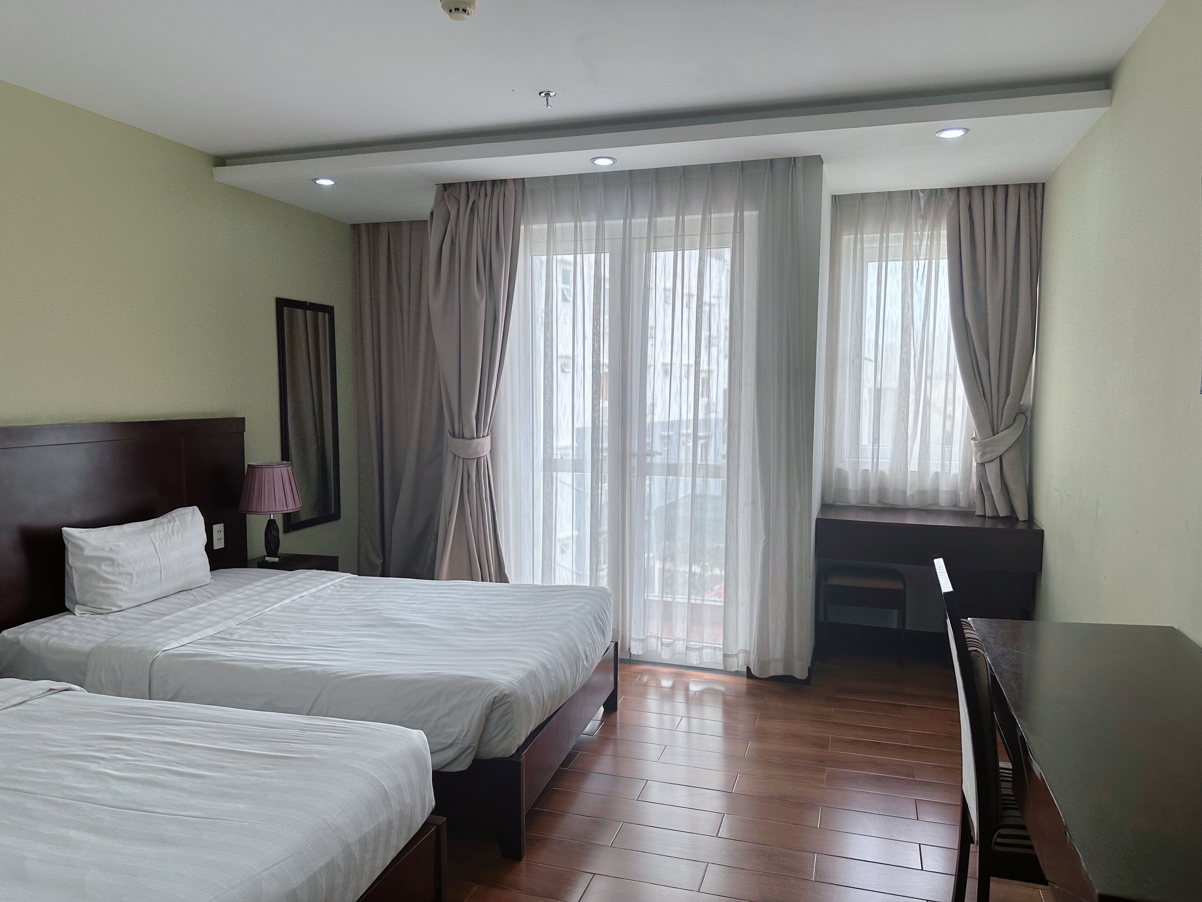 A hotel room with two beds, a desk, and a chair.