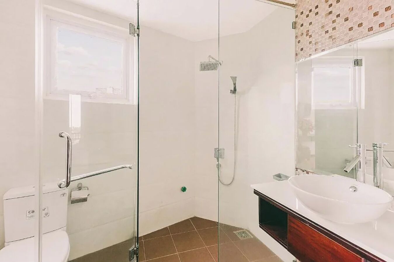 Un baño moderno con cabina de ducha de vidrio, un lavabo blanco y un inodoro.