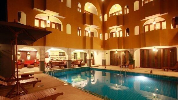 Ein Poolbereich mit Holzterrasse, Liegestühlen und einer Bar mit Sitzgelegenheiten.