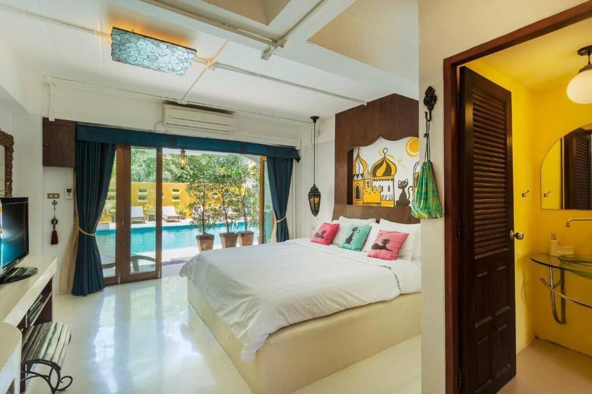 Une chambre avec un lit, une télévision, un bureau et une vue sur une piscine.