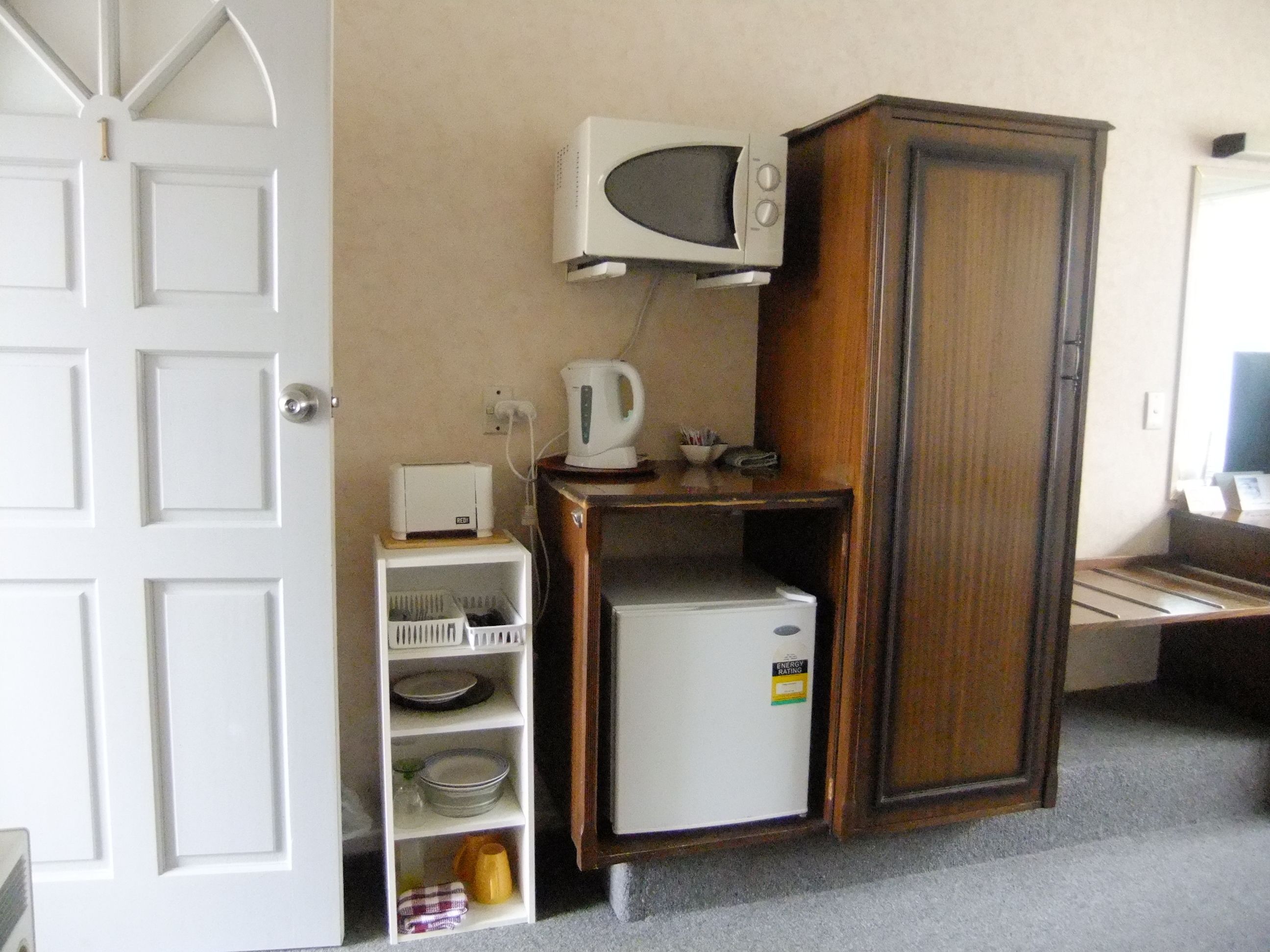 A compact kitchen with a microwave, a small refrigerator, and a cabinet.