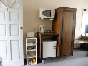 A compact kitchen with a microwave, a small refrigerator, and a cabinet. - Abbeycourt Motel (Lower Hutt)