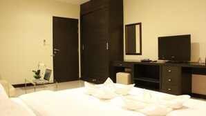 A hotel room with a bed, a desk with a laptop, a television, and a wardrobe.
