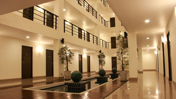 A multi-level hotel lobby with a central reflective pool, potted plants, and a modern design.