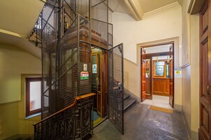 Un interno su più livelli con una scala in metallo, porte in legno e vista su un'area con un bar.