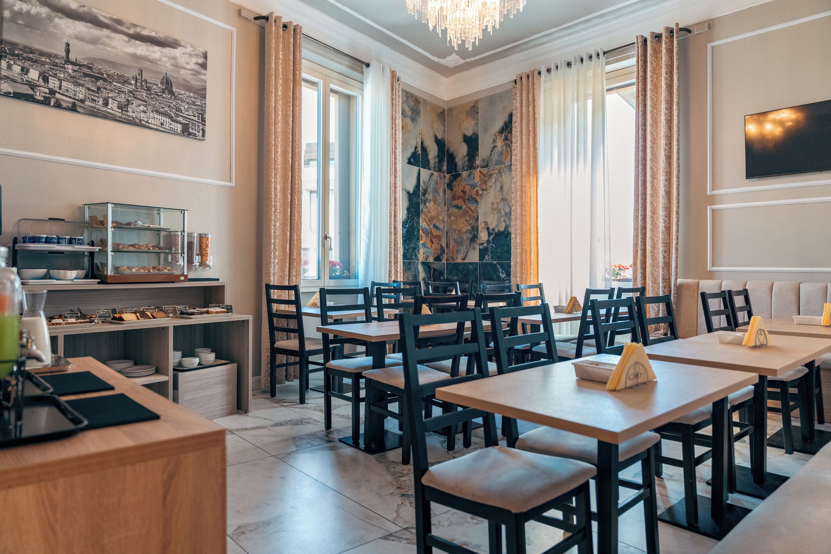 A restaurant with multiple tables and chairs, a coffee station, and a large window with curtains.