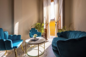 Una stanza con un divano blu, una poltrona coordinata e un tavolino con un vaso di fiori.
