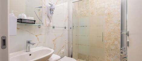 A bathroom with a white sink, a toilet, and a glass-enclosed shower.