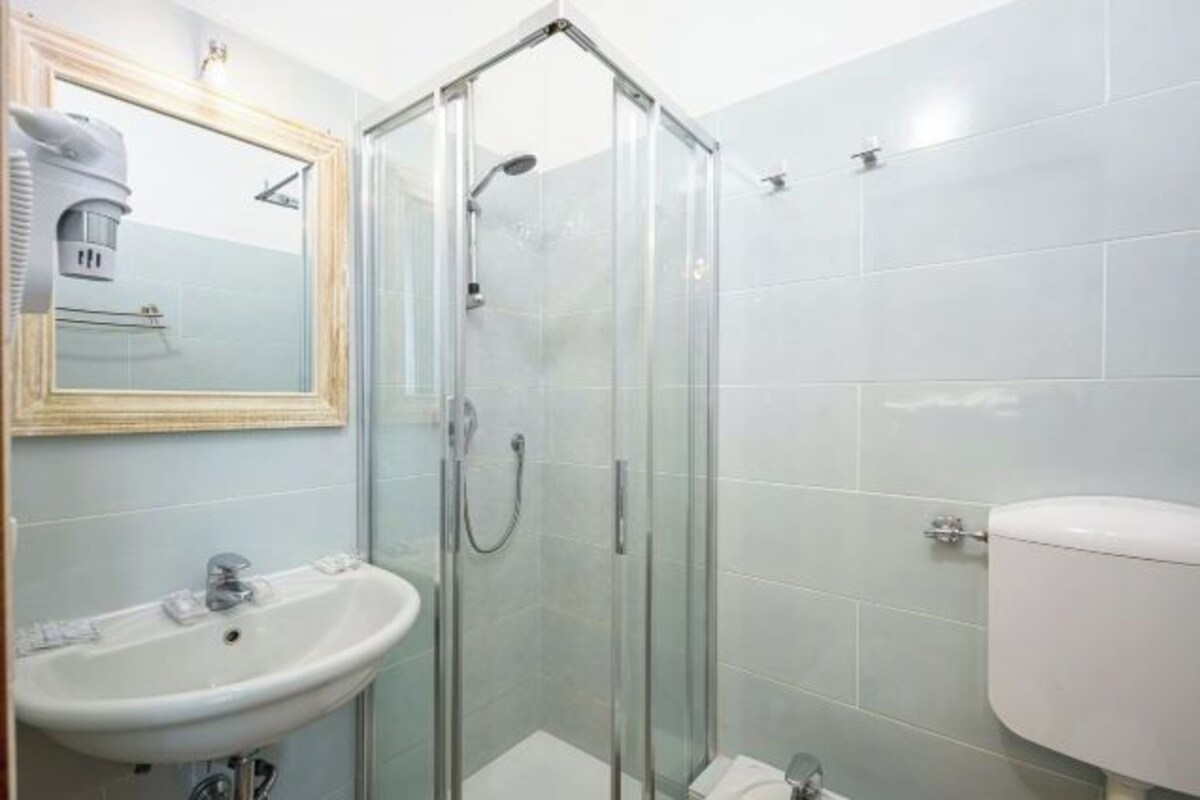 A bathroom with a glass-enclosed shower, a sink, and a toilet.