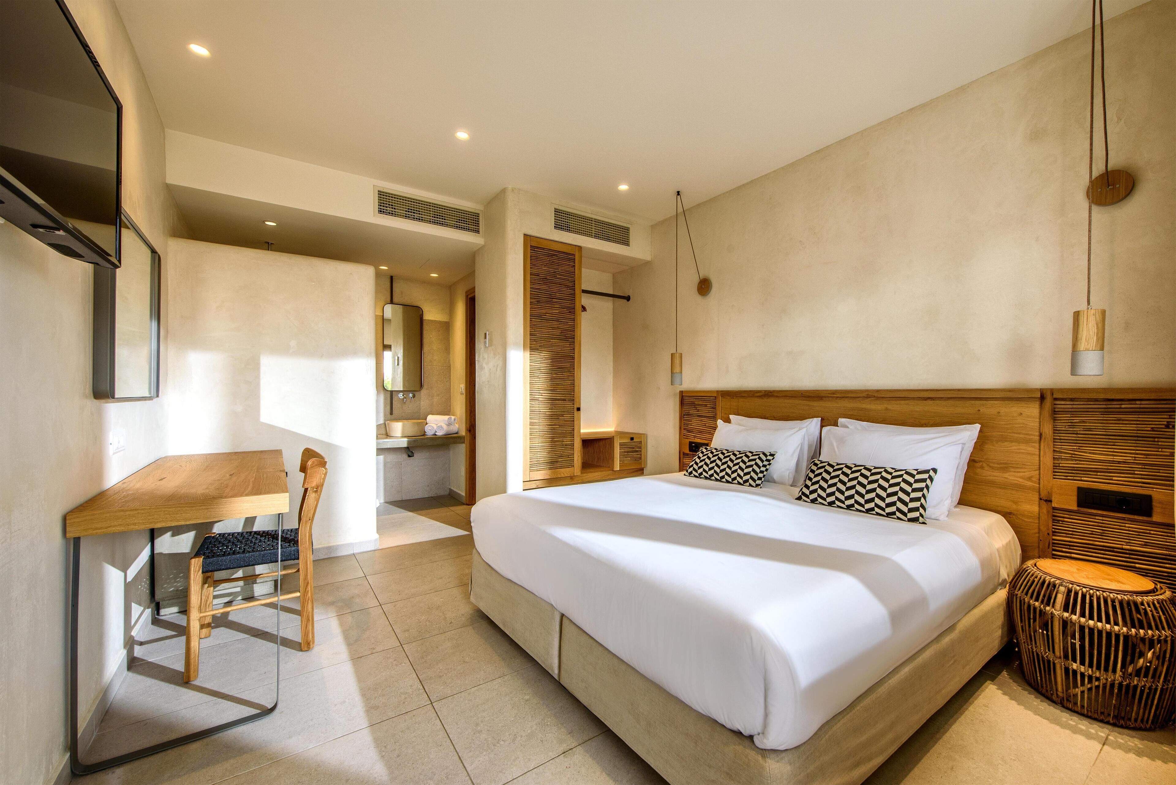 Una moderna camera d'albergo con un letto grande, una scrivania in legno e un piccolo tavolo rotondo.