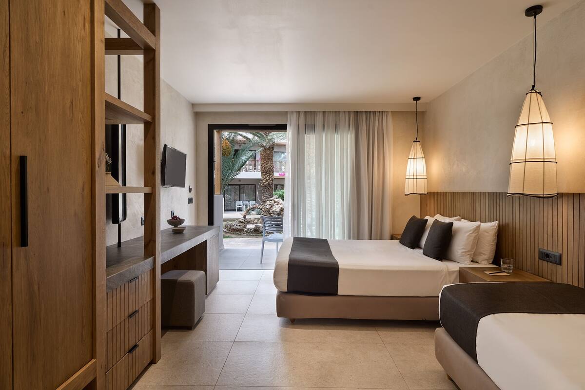 Een hotelkamer met twee bedden, een bureau, een televisie en uitzicht op het buitengebied.