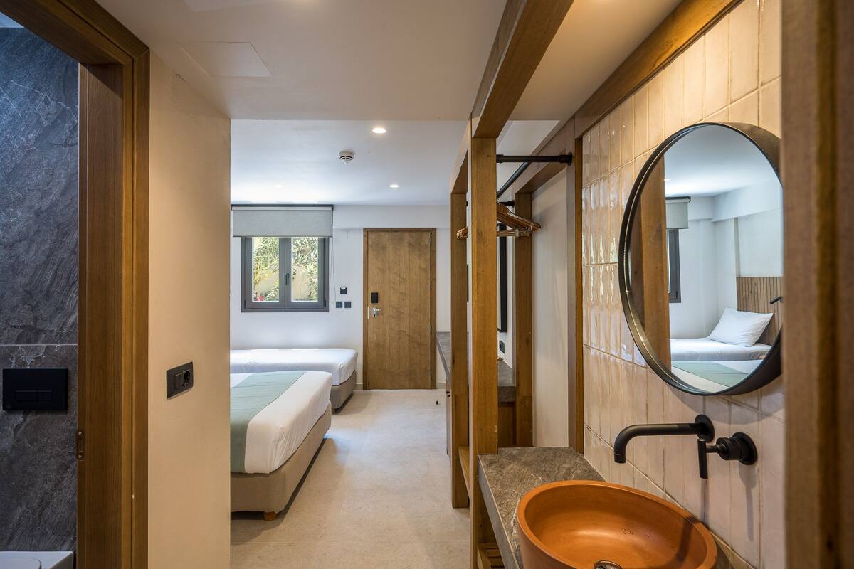 Een moderne hotelkamer met een grote spiegel, een houten opbergmeubel en een groot raam.