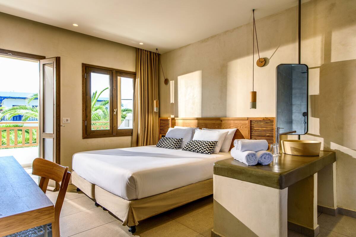 Hotelkamer met een bed, bureau, badkamer met wastafel en uitzicht op het omliggende landschap.