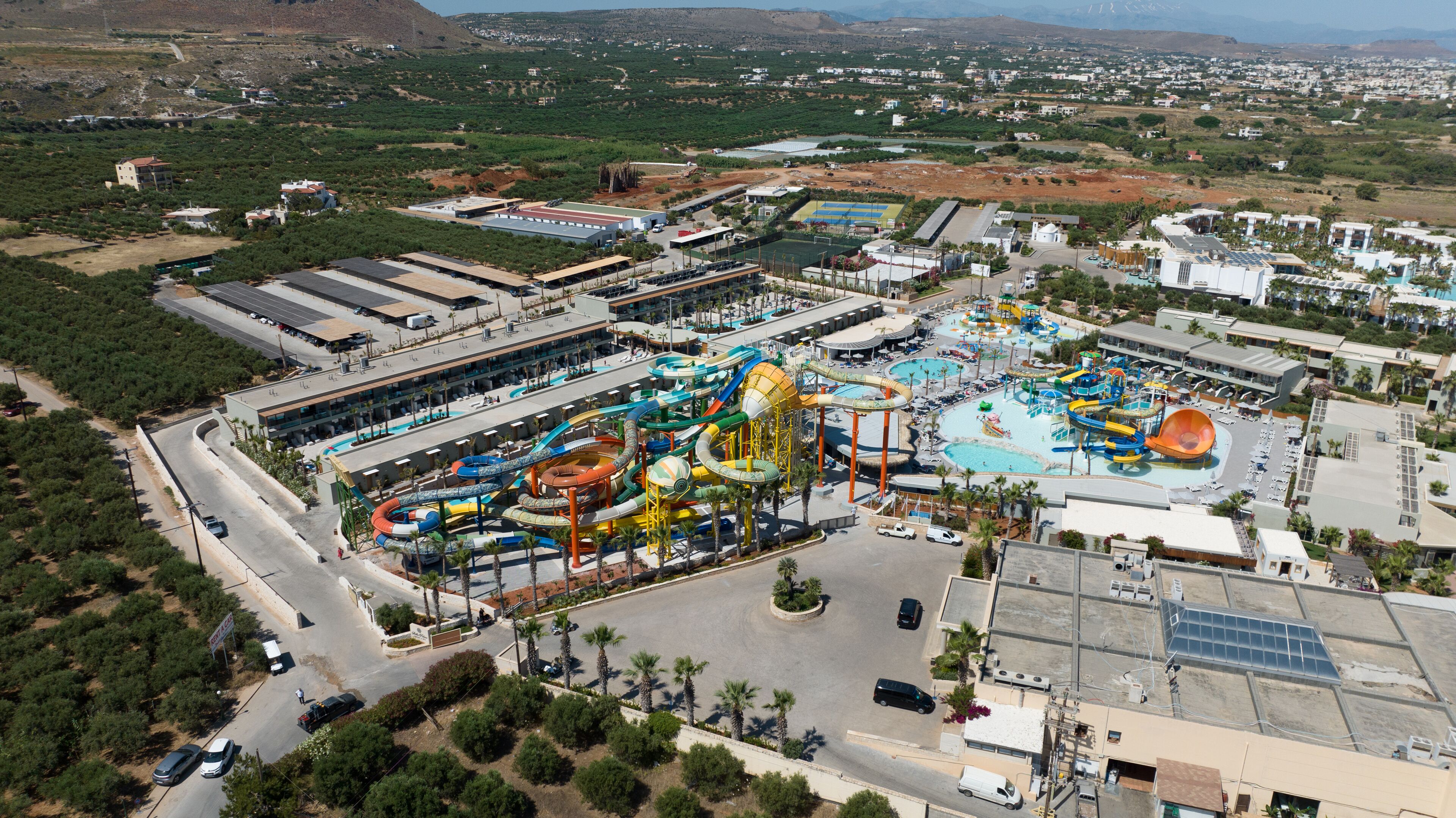 An aerial view of a resort with a water park, multiple buildings, and a parking area.