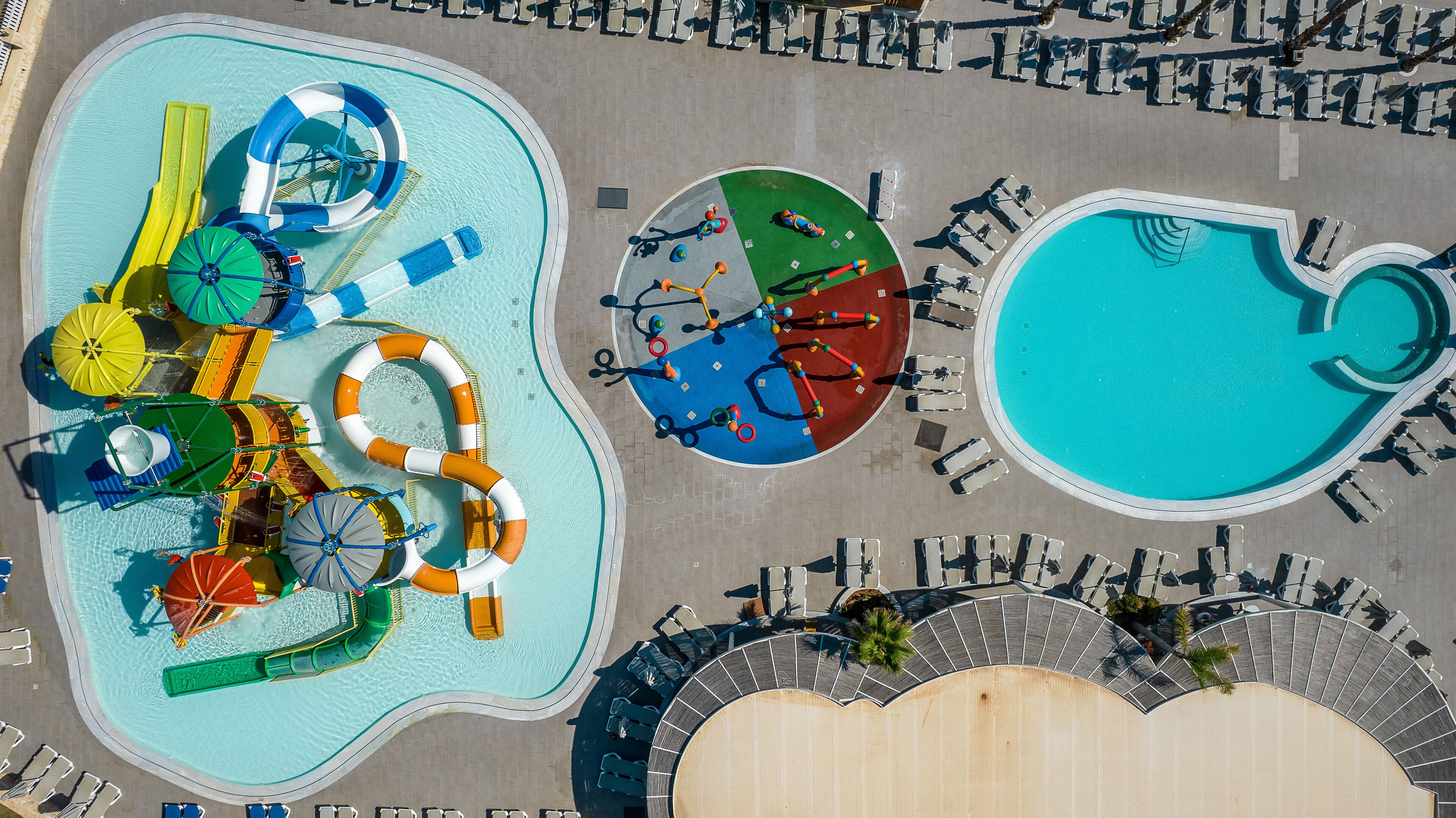 An aerial view of a water park with multiple pools, slides, and a seating area.