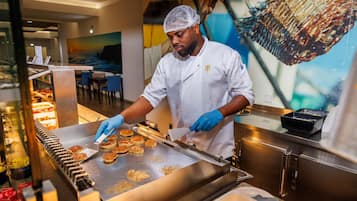 Um chef preparando comida em uma cozinha moderna com um sistema de esteira transportadora.