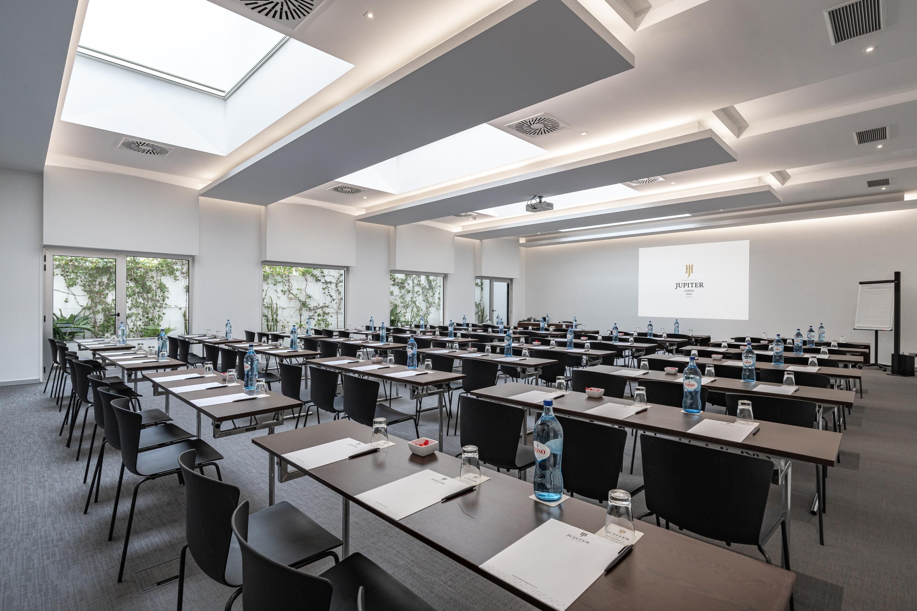 A conference room with tables, chairs, and a projector screen displaying "JUPITER".