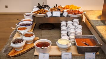 Un buffet proposant une variété de plats et d’accompagnements, notamment du miel, du lait concentré et une pâte à tartiner au chocolat.