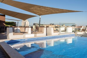 A rooftop pool with blue tiled edges, beige lounge chairs, and a large canopy. -  Jupiter Lisboa Hotel – Rooftop & Spa (Lisbon)