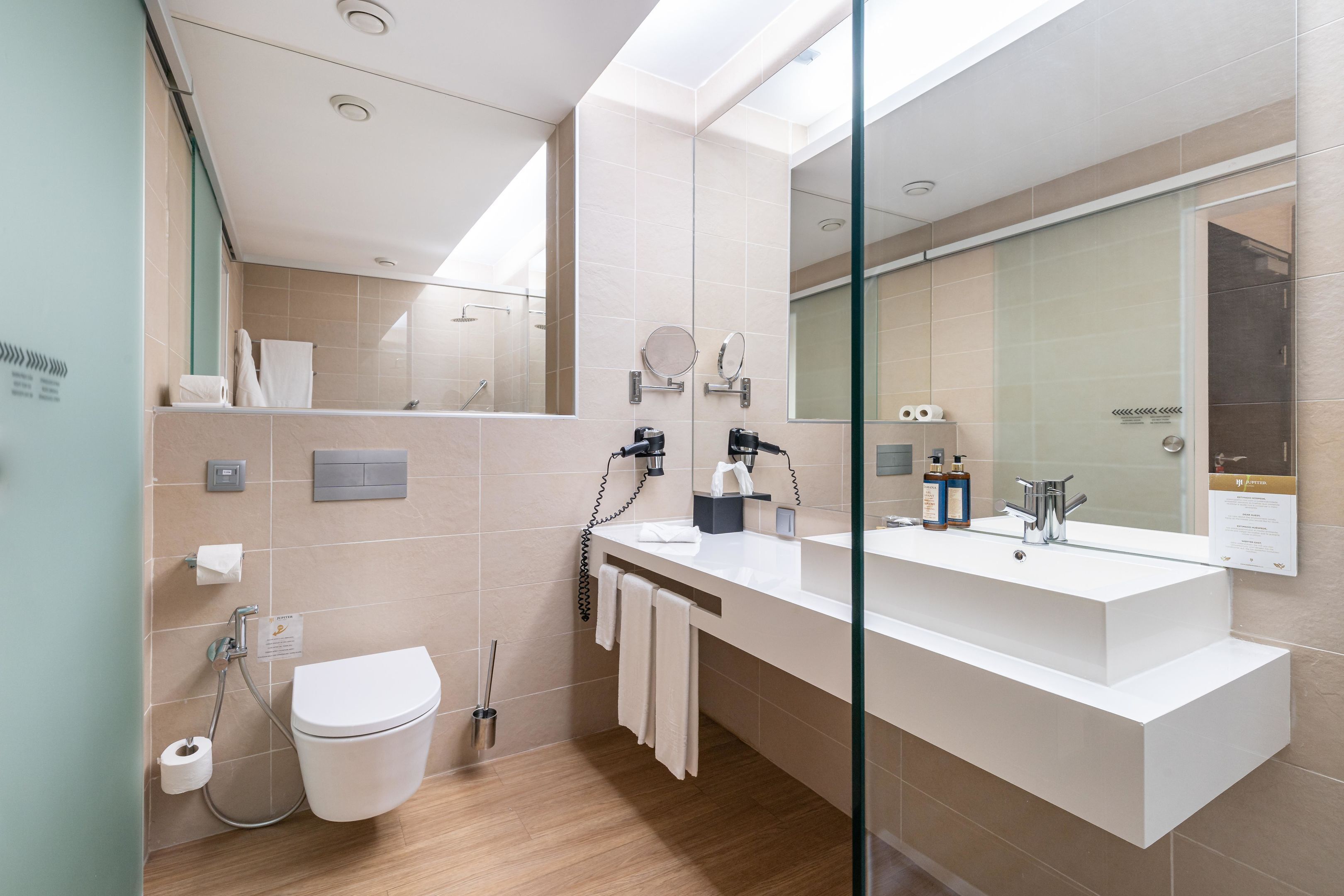 Un baño moderno con un espejo grande, un inodoro y una zona de ducha.