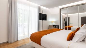 Habitación de hotel moderna con una cama grande, un televisor de pantalla plana, un escritorio y un espejo.