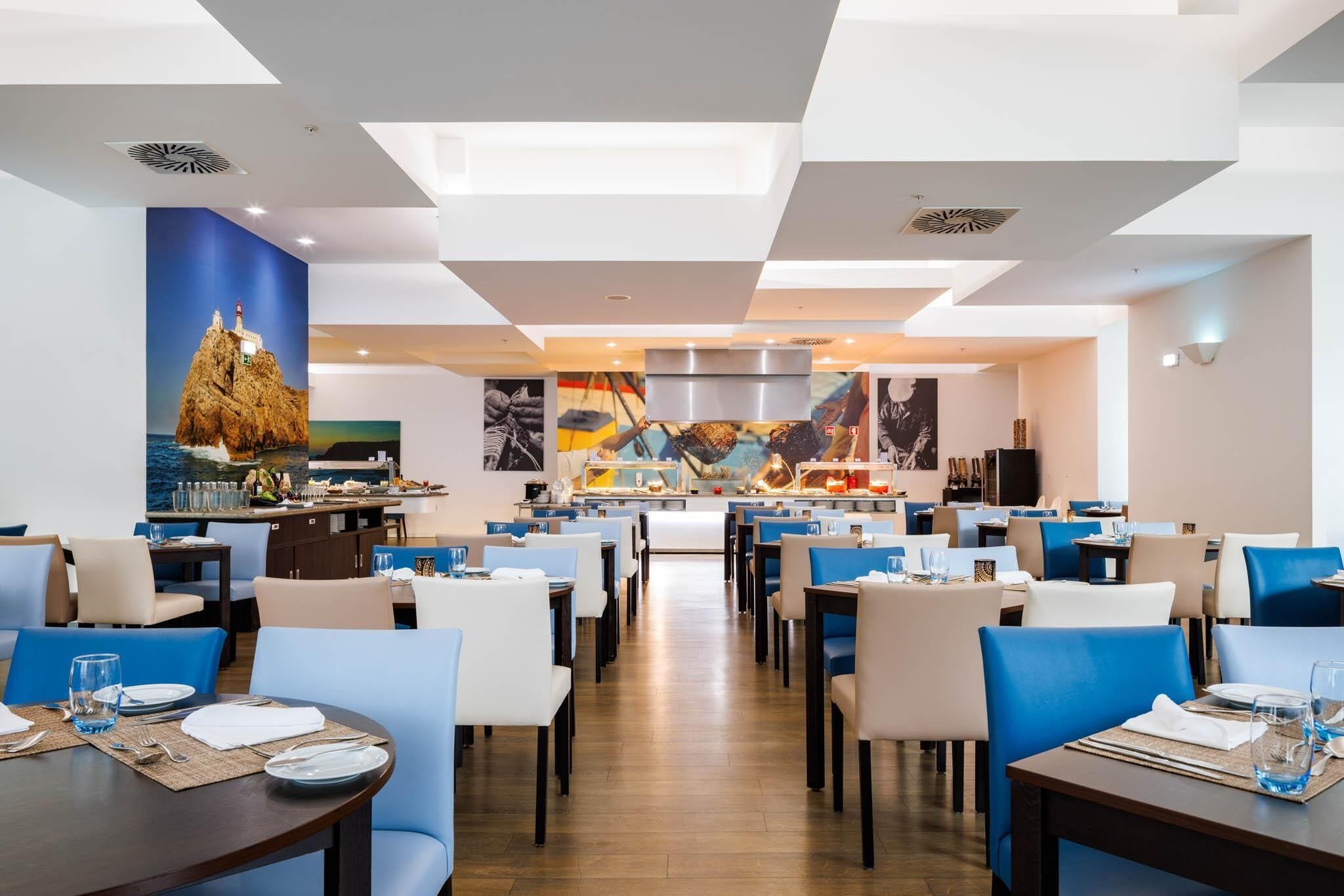 Un restaurante moderno con una isla central, asientos blancos y azules y decoración de temática náutica.