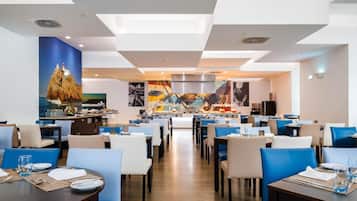 Un restaurante moderno con una isla central, asientos blancos y azules y decoración de temática náutica.